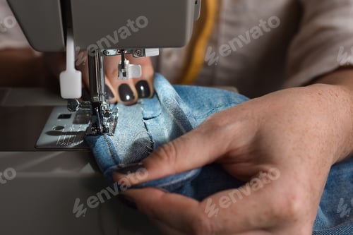 Preview: Seamstress using sewing machine to hem jeans pants