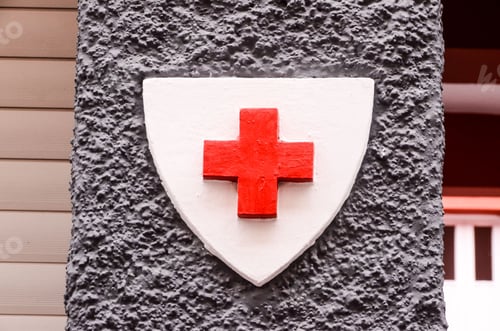 Preview: Red cross medical sign on a concrete wall on a building