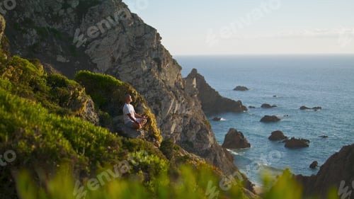 Preview: Serene person meditating ocean view. Calm man resting practicing yoga at cliff