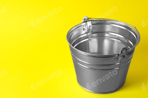 Preview: One shiny metal bucket on yellow background. Space for text