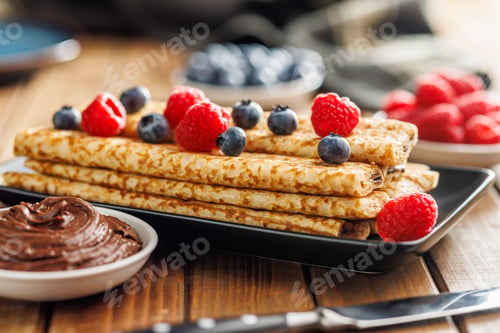 Preview: Delicate crepes stacked with blueberries and raspberries, served with a chocolate spread.