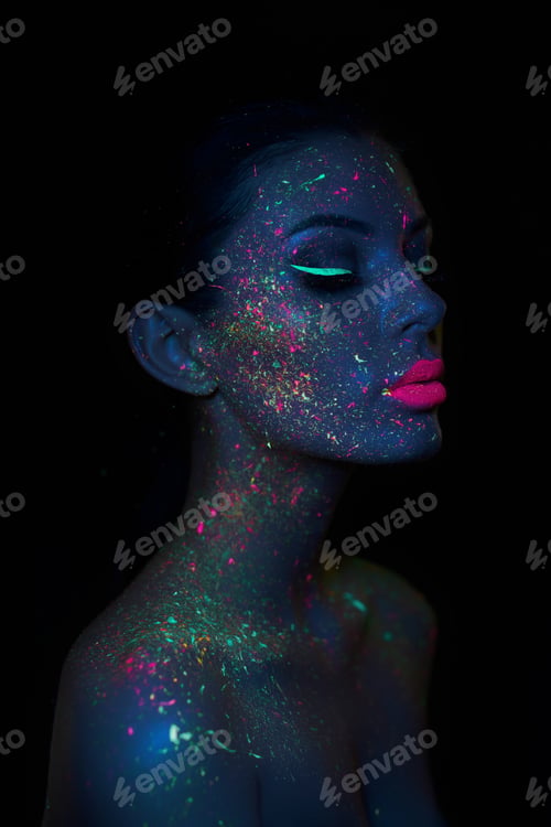 Preview: Fashion model woman in neon light bright fluorescent makeup, drop on face. Beautiful model