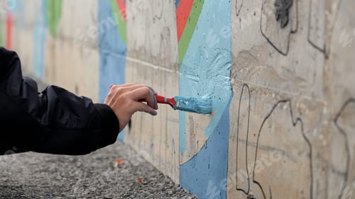 Preview: Male teenager hand painting a wall in blue color with a paint brush. Clip. Talented student creating