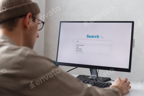 Preview: Unemployed man looking for work on the internet sitting at the computer at home