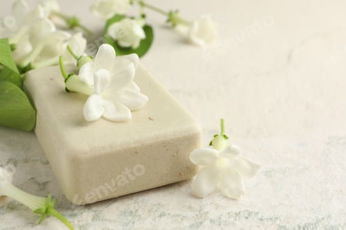 Visualização: Barra de sabão e flores de jasmim na mesa de luz, closeup. Espaço para texto