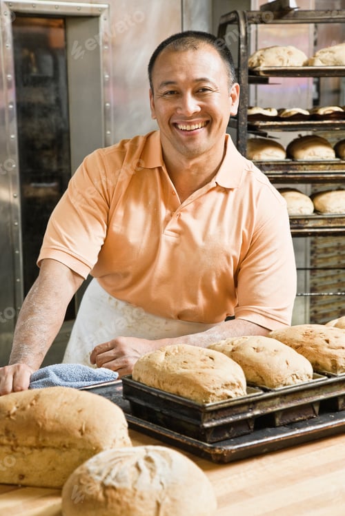 Preview: Hispanic man baker and some of the loaves of bread he baked this morning.