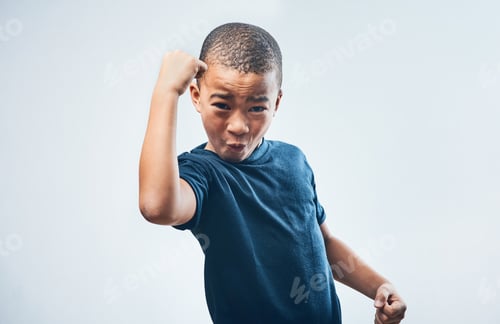 Preview: Studio shot of a cute little boy flexing his muscles against a grey background