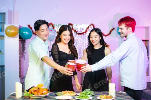 Visualização: jovens amigos levantam copos vermelhos para comemorar em um divertido jantar interno com comida, risadas,