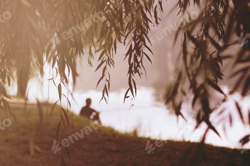 Preview: Lonely fisherman sitting in the riverbank