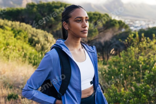 Preview: Portrait of young female in sportswear with backpack standing outdoors at sunset