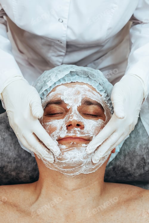 Preview: Beautician applying scrub mask on face to young man, spa beauty salo, of body and face care for men