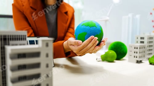Preview: A businesswoman in a brown suit stands at a white desk with a world model, an electric car model