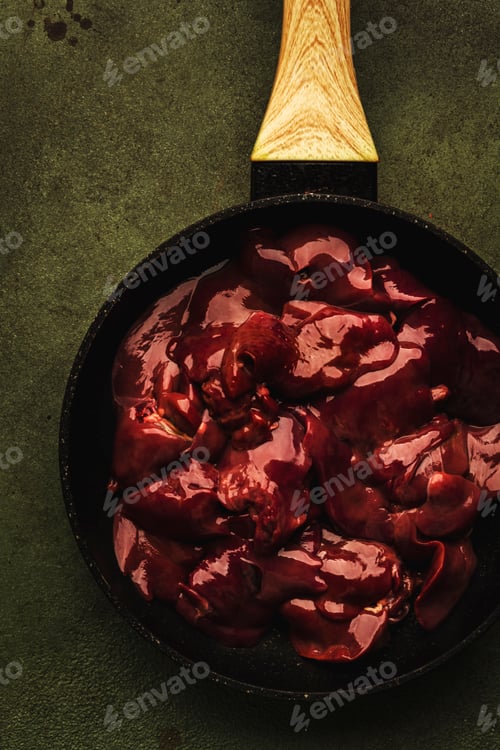 Preview: Fresh raw chicken liver in frying pan and ingredients for cooking on concrete green kitchen table