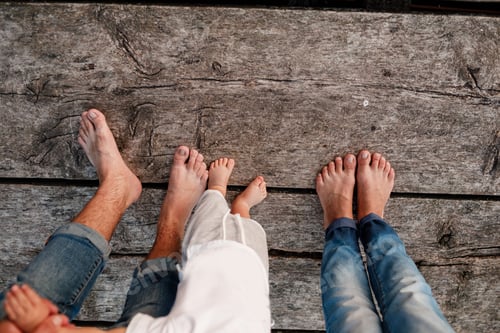Preview: Mom, dad and baby walk bare feet on the wooden bridge. Happy young family spending time together,