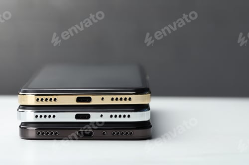Preview: Stack of modern smartphones on white table, closeup. Space for text
