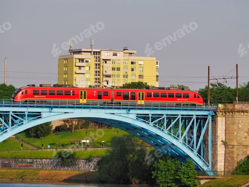 Preview: Vibrant red train travelling across a bridge