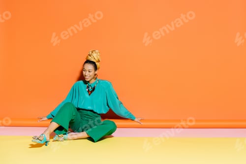 Preview: Carefree african american model in summer clothes sitting on colorful background