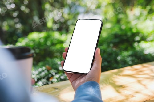 Preview: Mockup image of a woman holding mobile phone with blank white desktop screen in the outdoors