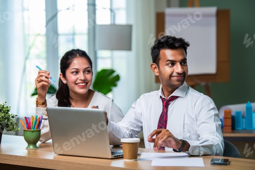 Preview: Indian asian young CEO businessman working with female colleague in the office using laptop computer