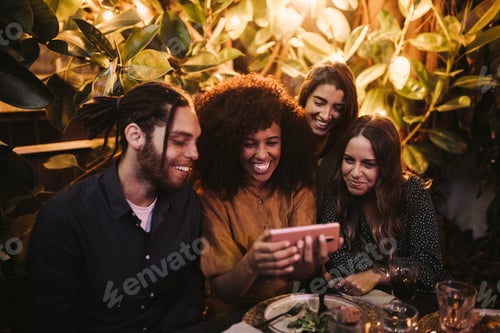 Preview: Group of young adult friends looking at phone having fun at party