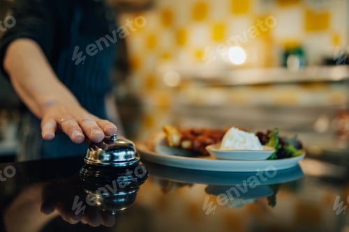 Preview: Chef ringing service bell for ready meal in restaurant kitchen