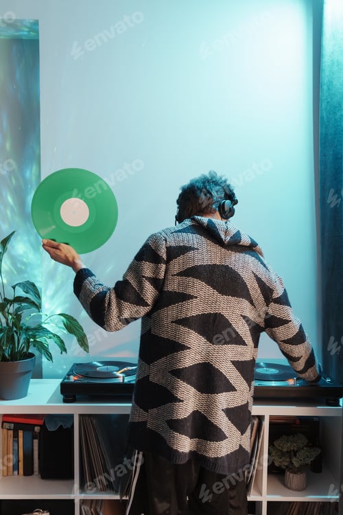 Preview: Man holding vinyl record near turntable in cozy room