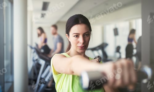 Preview: Beautiful woman doing exercises with dumbbell in gym. Girl is enjoying with her training process