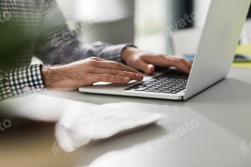 Preview: Young man using laptop at desk in office