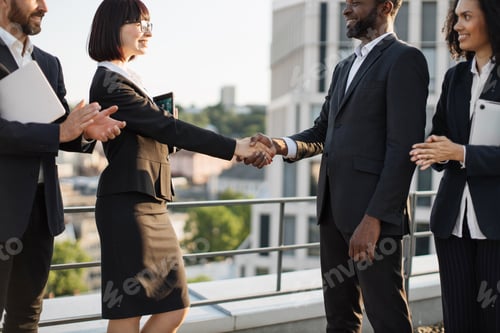 Preview: Diverse colleagues shaking hands after negotiations on roof