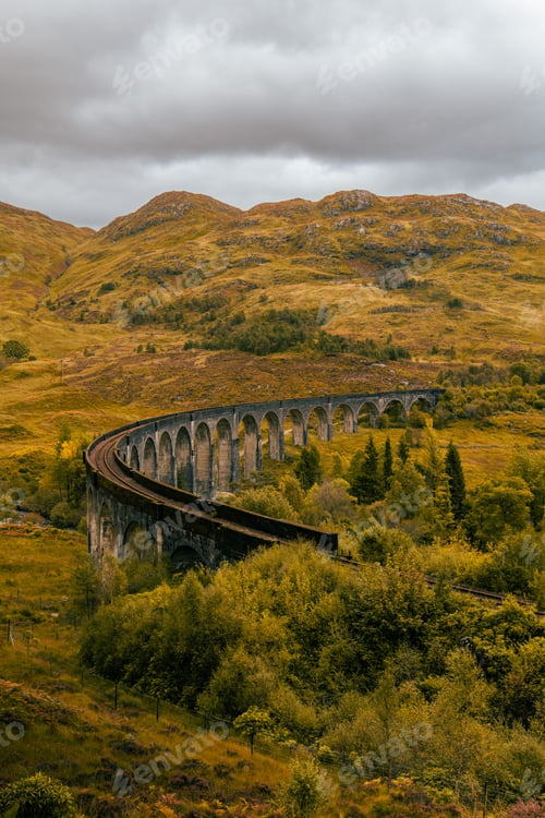 Preview: Scenic view of a train railway bridge over a lush landscape of mountains and grass
