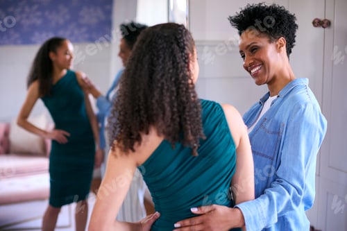 Preview: Mother Helping Teenage Daughter In Bedroom At Home Getting Ready For Prom Or Night Out