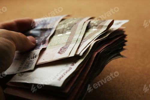 Preview: Closeup shot of a male hand holding a pack of Russian Ruble banknotes