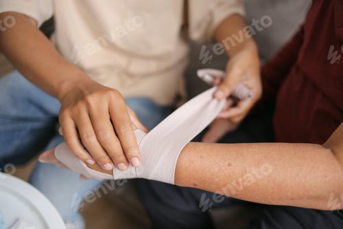 Preview: Close-Up Of Young Man Hands Helping With Wrapping Elastic Bandage. Wounded Hand Cover With Bandage