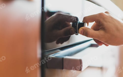 Preview: Married man is twisting the handle of an oven at home. Cooking in the kitchen