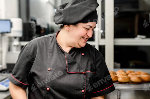 Preview: Woman chef in black uniform working at the kitchen of the restaurant