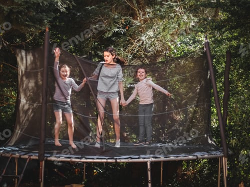 Preview: Three beautiful caucasian sister girls in jeans, shorts and a sleeved t-shirt jump on a trampoline