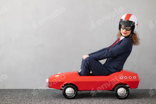 Preview: Successfull businesswoman driving toy car outdoor
