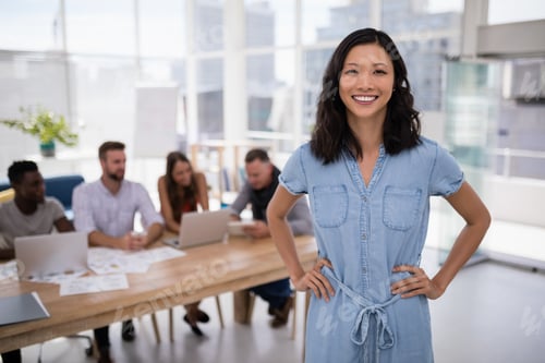 Preview: Female executive standing with hands on hip in the office