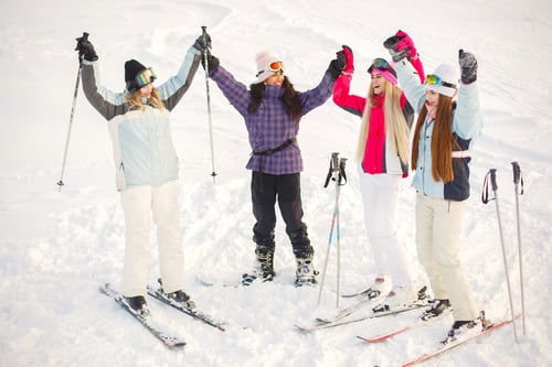 Preview: Girls posing against backdrop of mountains in ski gear.