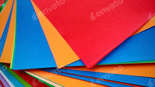 Preview: Stack of multicolored origami papers on a gray stone or concrete background.