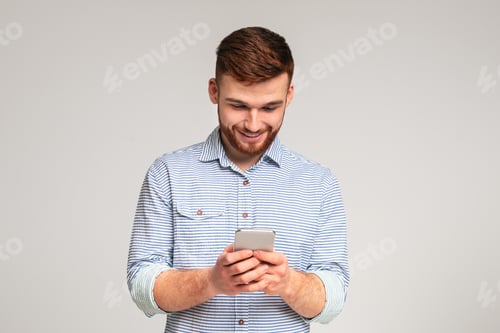 Preview: Young man absorbedly text messaging on his cellphone