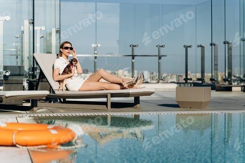Preview: Slender, modern girl with a dog in her arms resting by the pool. Beautiful blonde is resting