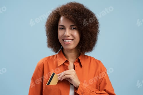 Preview: Smiling African American business woman hand puts credit card in pocket. Successful business concept