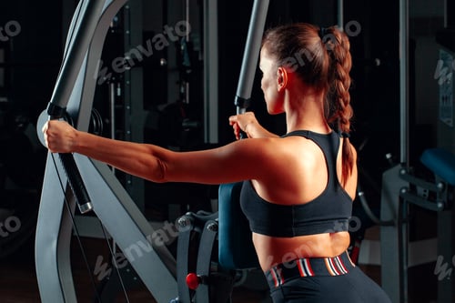 Preview: Young attractive woman doing exercises for arms in a training machine