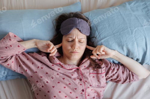 Preview: woman in bed wakes up, insomnia and sleep disorder. person in sleep mask holds his head and face