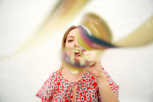 Preview: young woman blowing confetti against white background