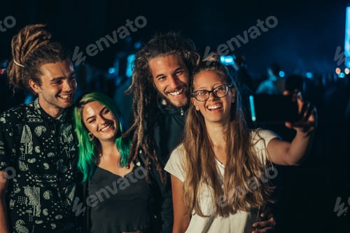 Preview: Friends at summer music festival taking selfie with a smartphone