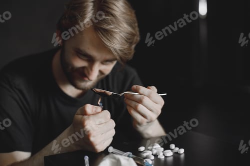 Preview: Addict preparing drug dose for injection in dark room