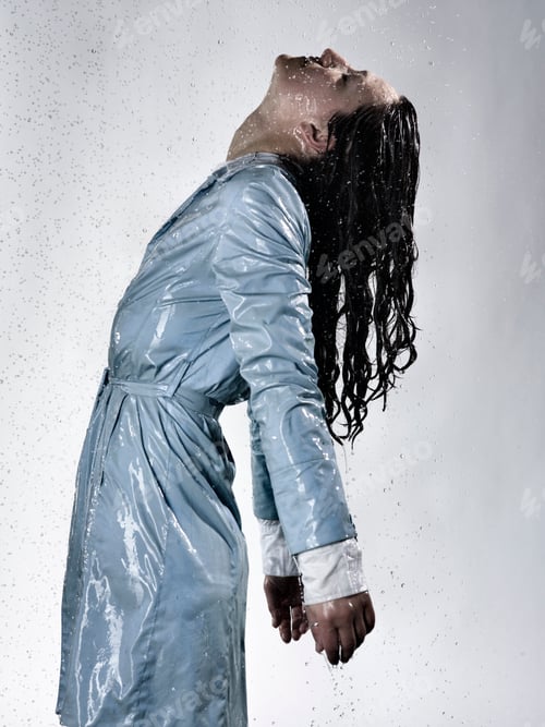 Preview: Side view of woman wearing raincoat drenched in water throwing back head
