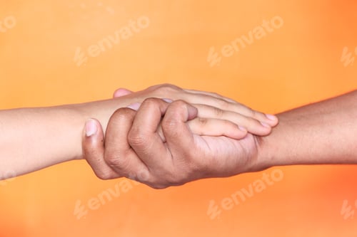 Preview: Close up of couple holding hands against orange background.